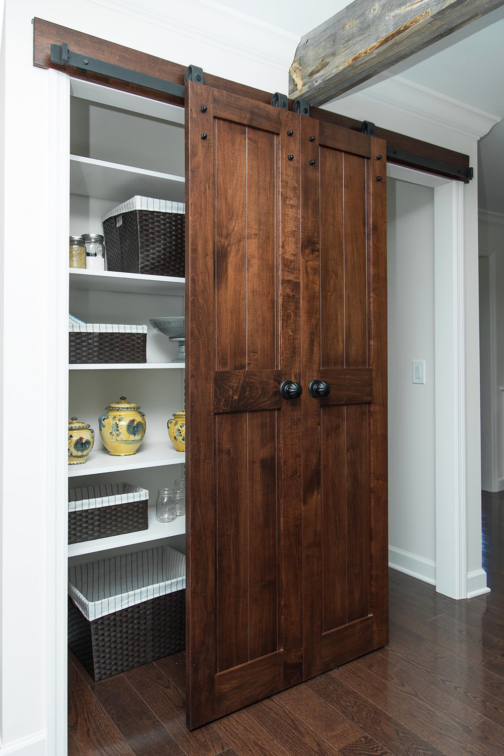 A small pantry nook covered by a sliding barn door made of reclaimed wood