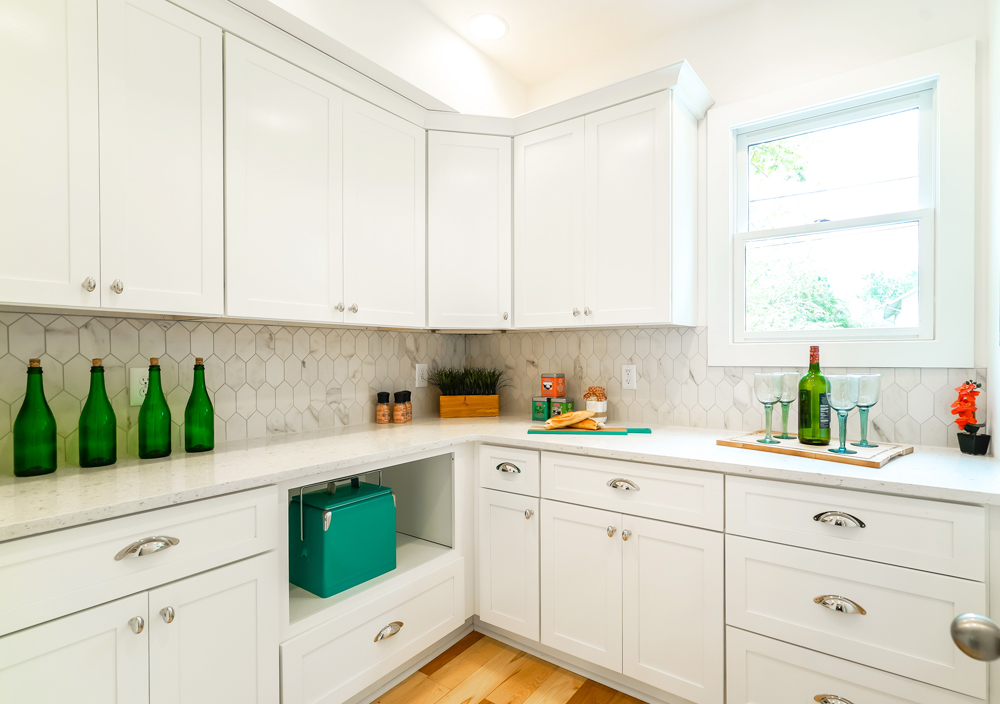 A white expansive walk-in pantry with tiled backsplash and plenty of storage