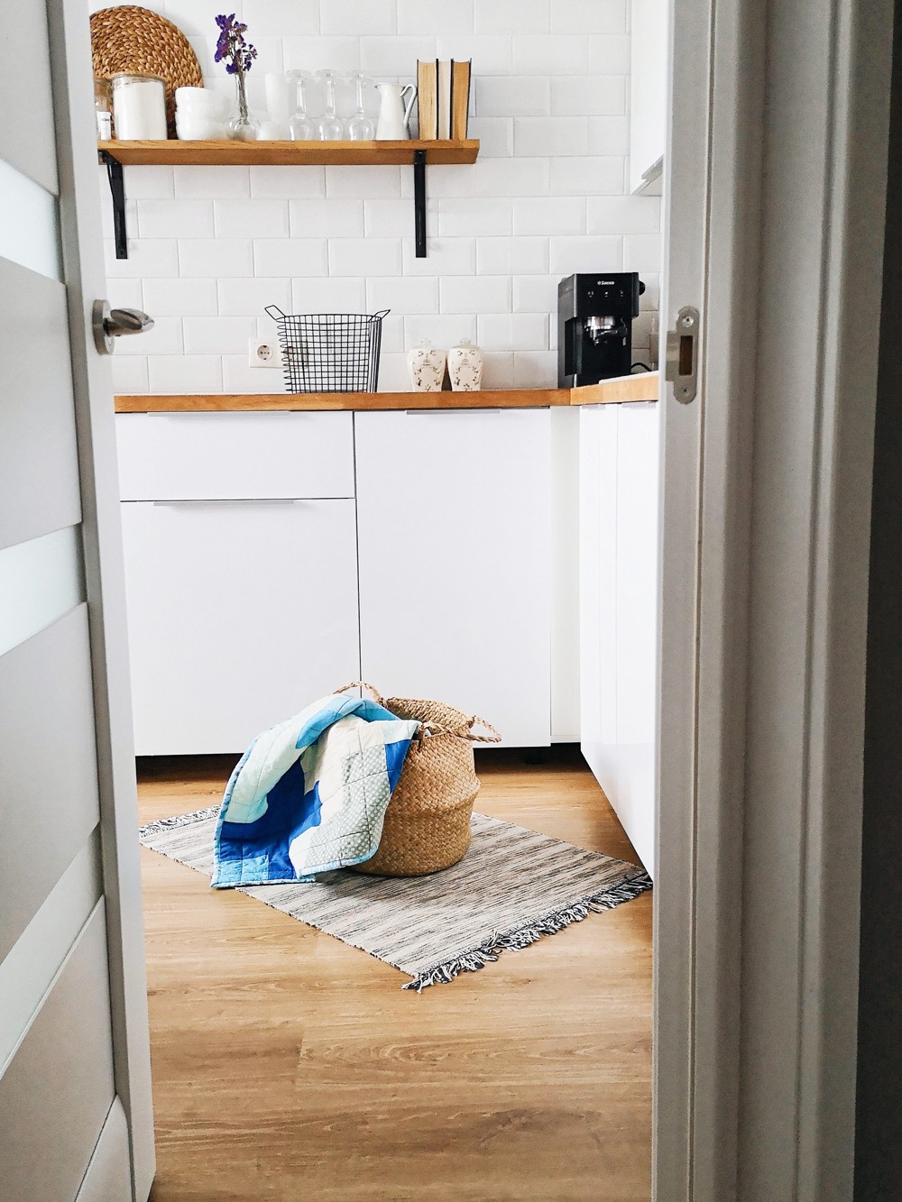 A white walk-in pantry contains storage space, open-shelving and some kitchen appliances