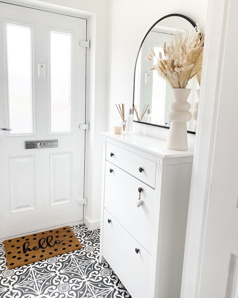 A soft white neutral foyer with a patterned tile floor