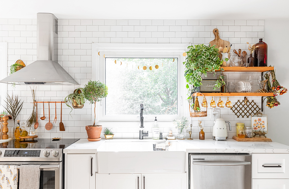 A pristine white kitchen with open shelving and plenty of plants