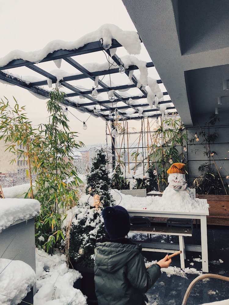 snowy winter balcony and a boy who built a snowman