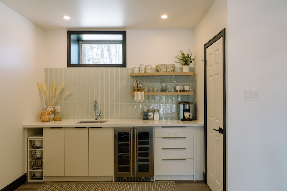 Basement kitchenette with white cabinets and neutral tile backsplash