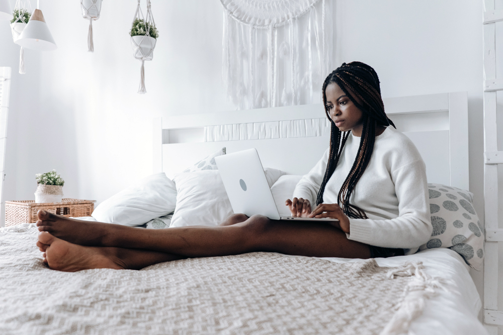 female working from her bed with her laptop