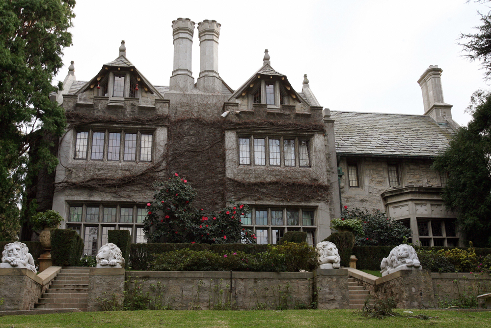 Exterior of the Playboy Mansion surrounded by a perfectly manicured lawn
