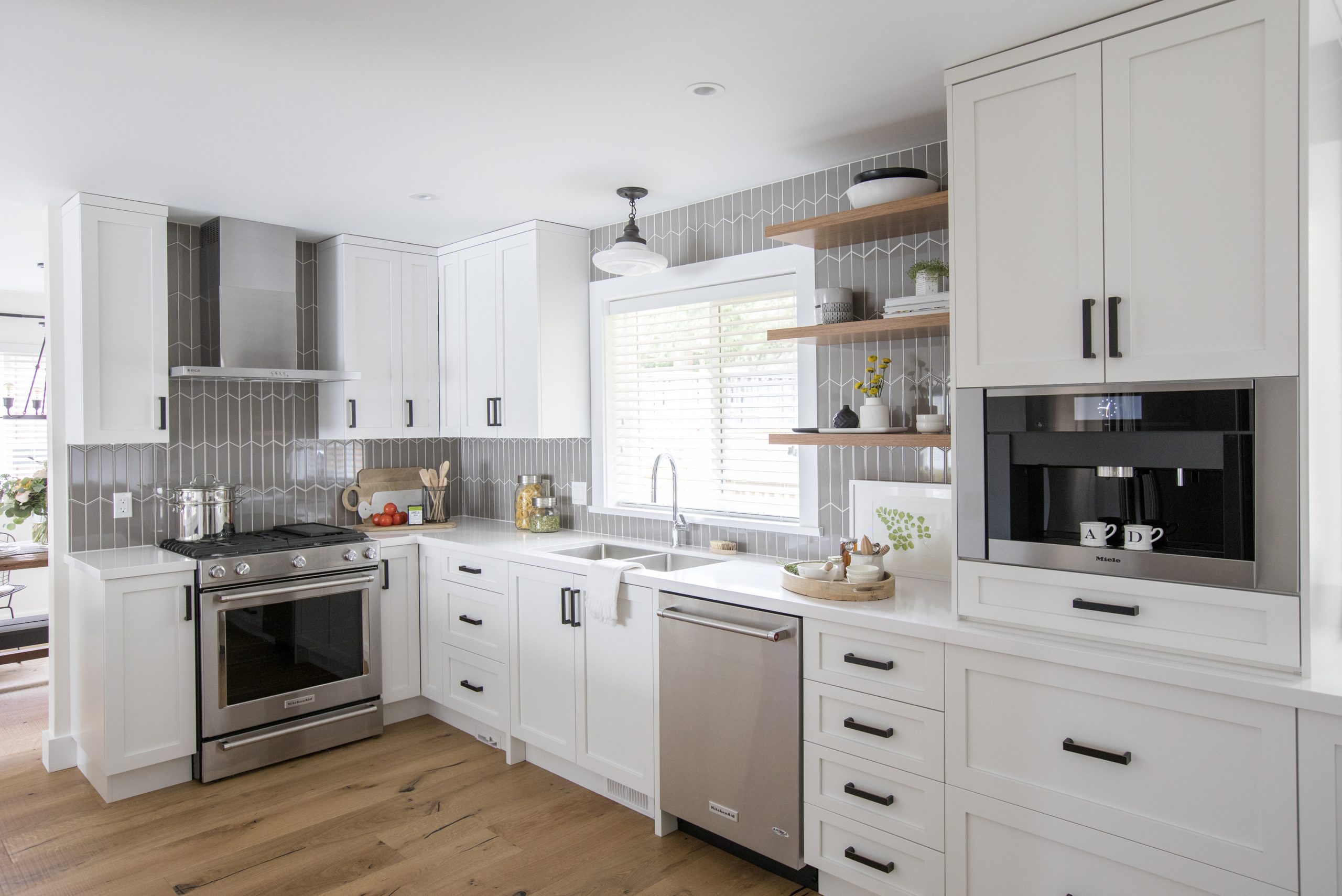 Modern white kitchen with grey tiled backsplash.