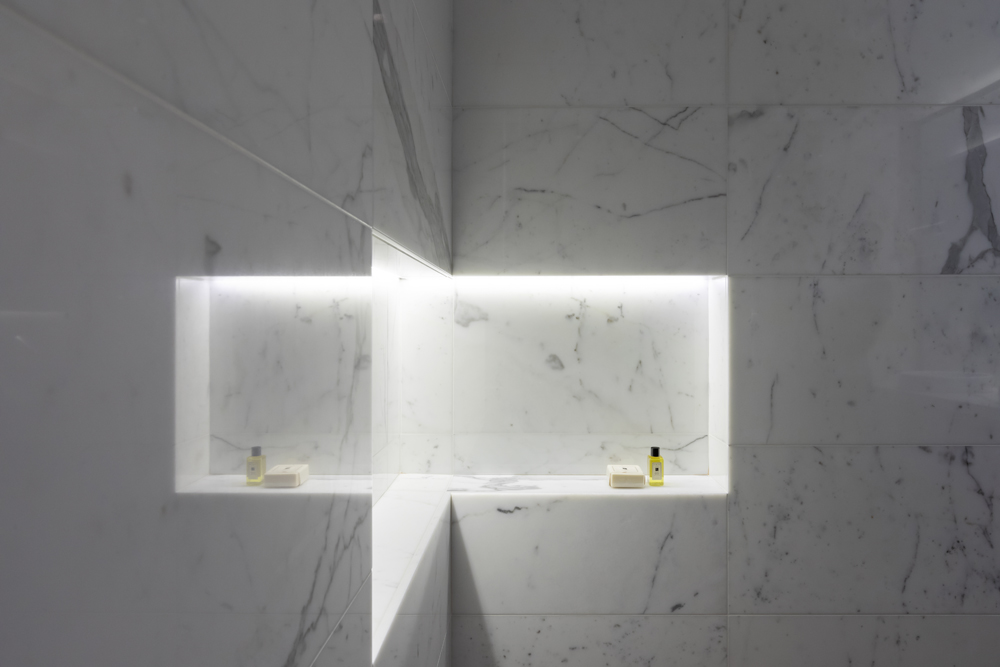 lit marble niche in bath with two jo malone products