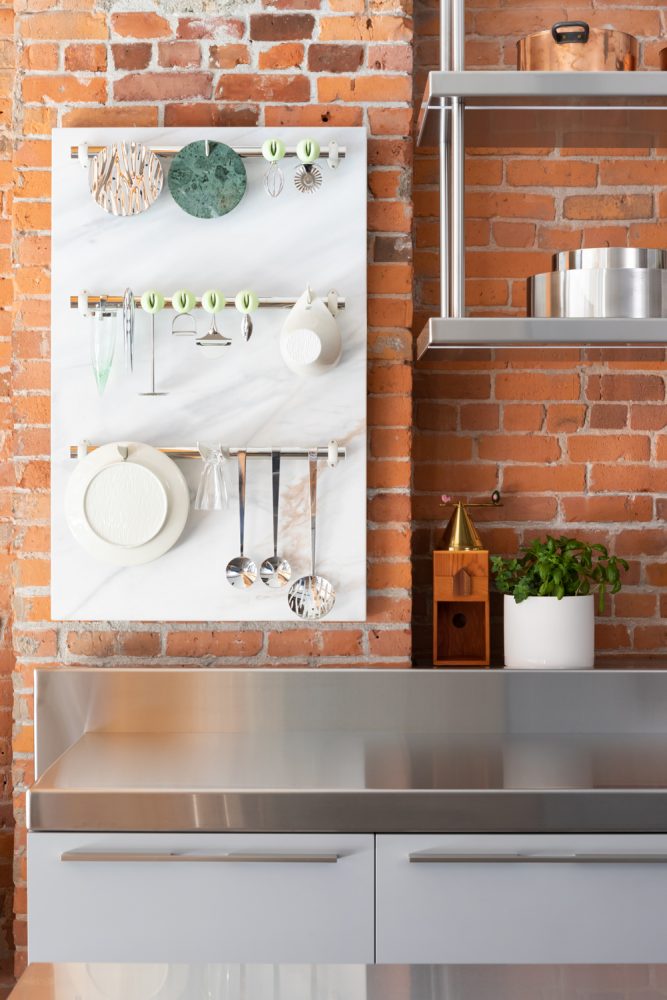 exposed brick wall kitchen, hanging utenils, stainless steel counter tops and white lower cabinets