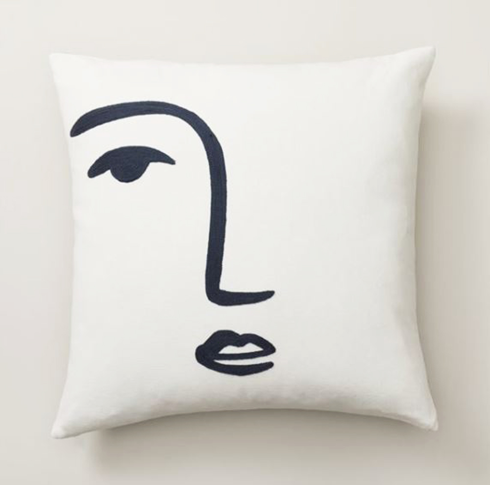 A white pillow cover with a drawn sketch of a person's face