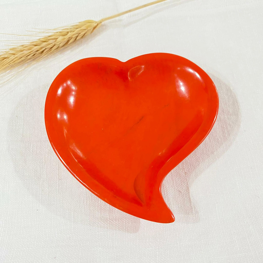 A red heart-shaped handmade stone soap dish against a white background