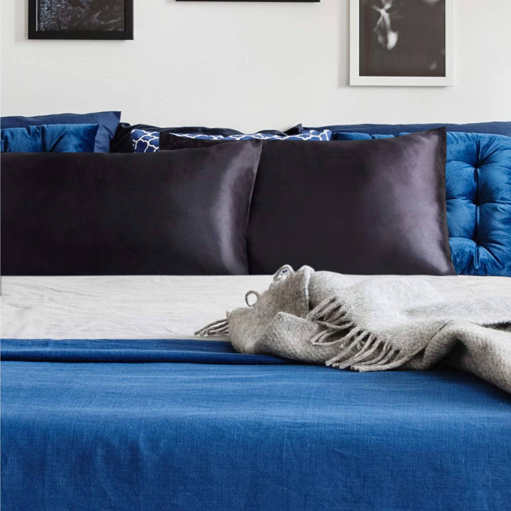 Black satin pillowcases on a bold blue bed