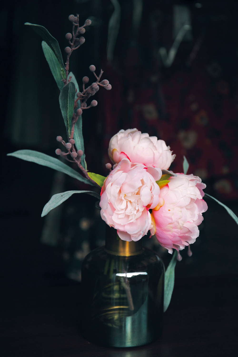 A tiny vase with a few peony flowers inside