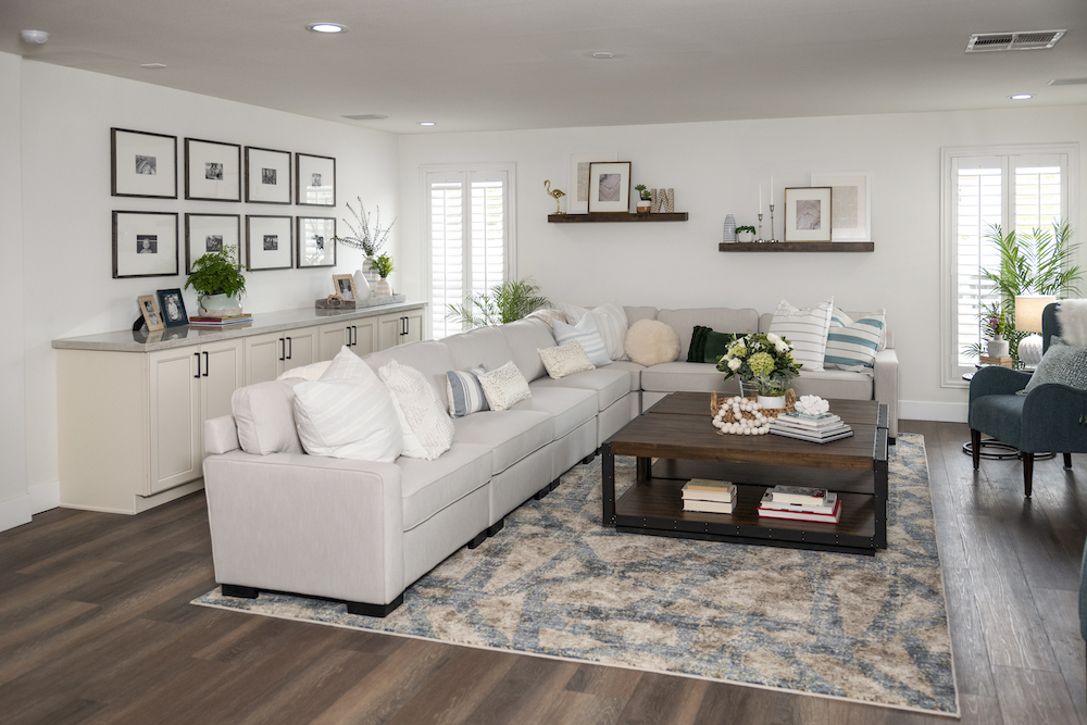 white living room with oversized sectional couch and framed photos on wall and shelves