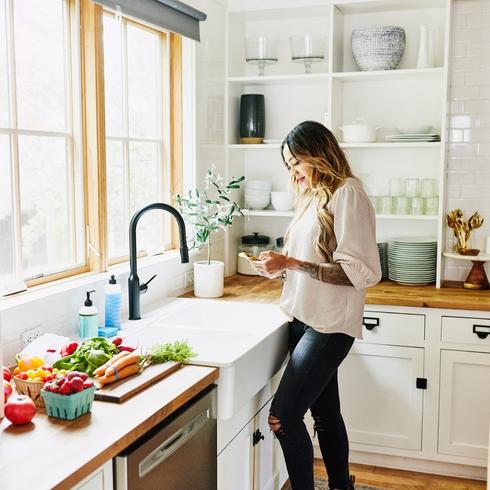 Woman reading phone in her organized kitchen