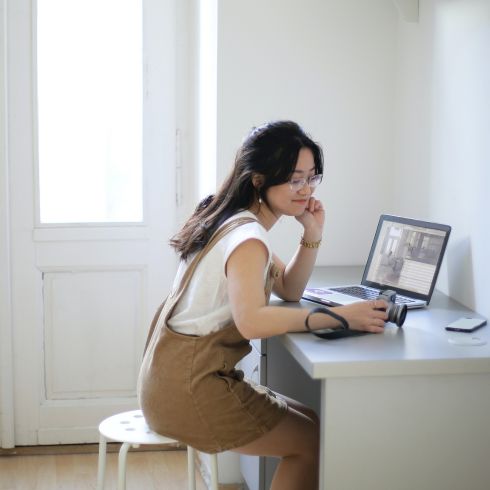 Woman typing on computer at desk in room