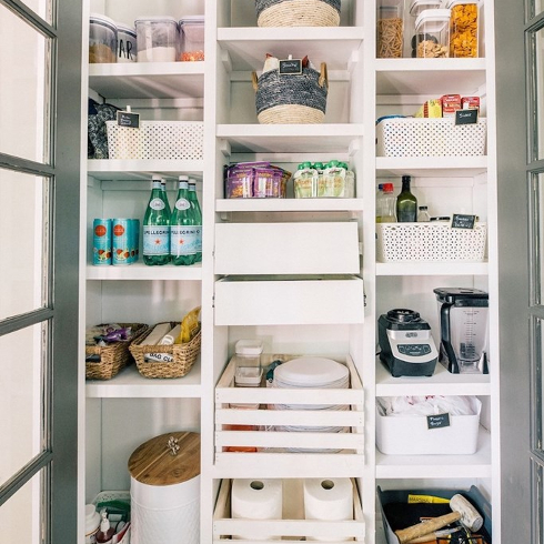 White organized pantry with doors on it