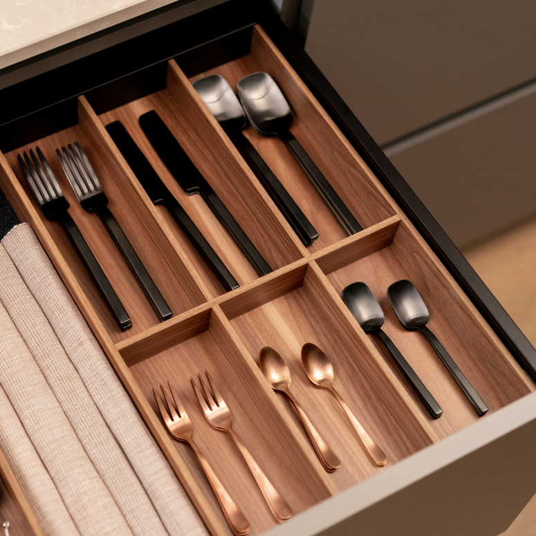 Sleek, wood cutlery drawer stocked with brass cutlery