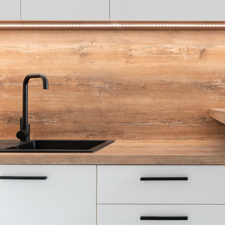 Modern kitchen with wood backsplash, white cabinets and sleek black hardware