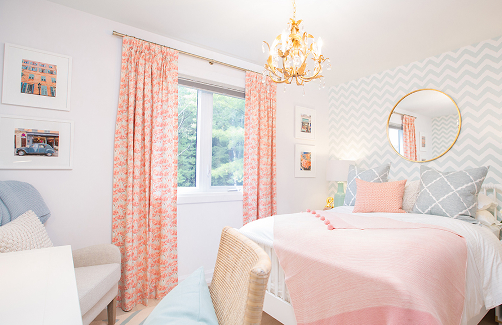 Beautiful bright bedroom featuring orange printed curtains, chevron wallpaper, a mix of prints and metallic hardware, and framed photos on a white wall as featured on Sarah Off the Grid on HGTV Canada