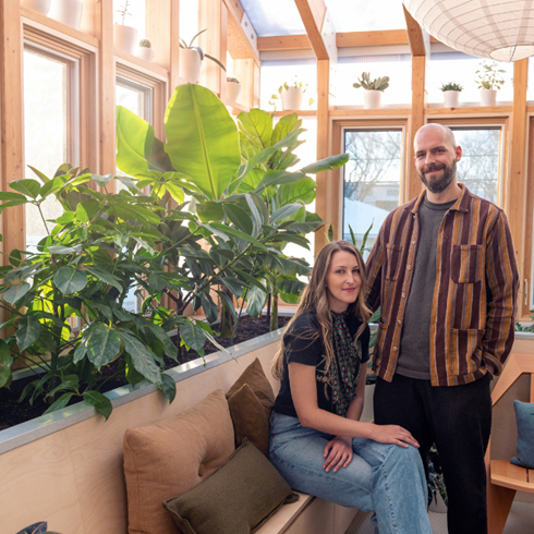 A shot of a young couple in an indoor sunroom with plenty of natural lights and plants