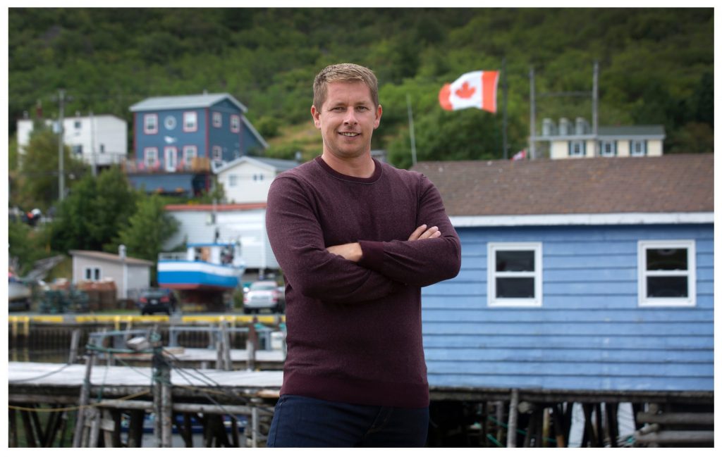Randy Spracklin wearing a sweater and smiling in front of a scenic harbourfront