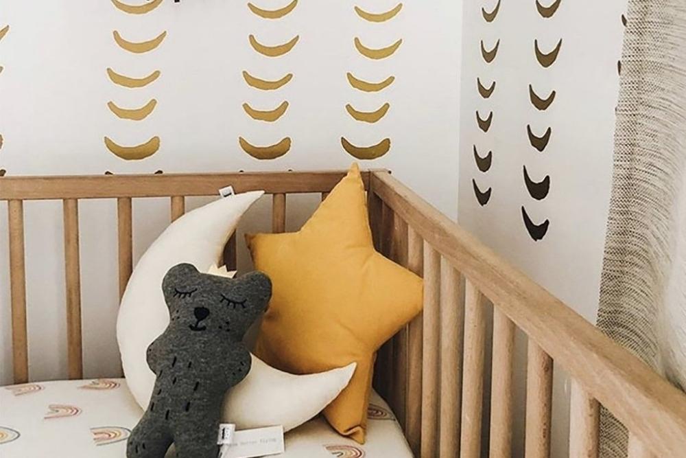 A crib in front of a wall with half moon gold wall decals