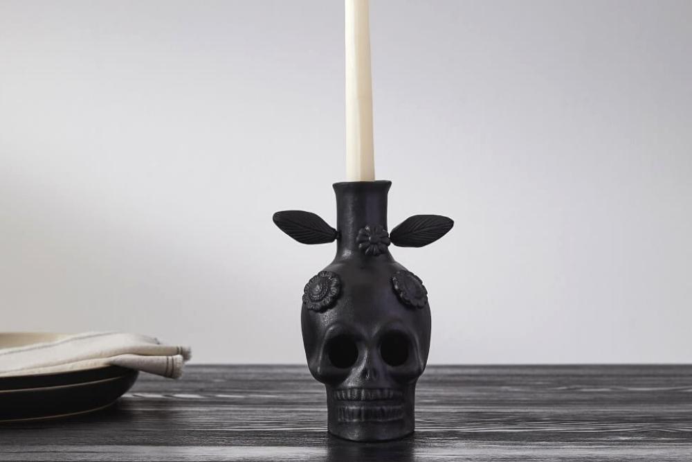 A black skull candle holder on a dining room table.
