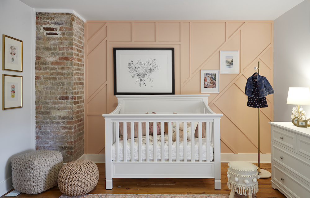 peach-coloured nursery with wall-panel details and white crib
