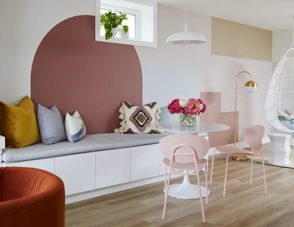 Breakfast nook in with a feature wall with pink colour blocked shapes painted on as seen on Save My Reno on HGTV Canada