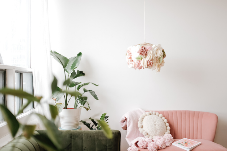The finished DIY lampshade hangs in a living room with a pink sofa and indoor plants.