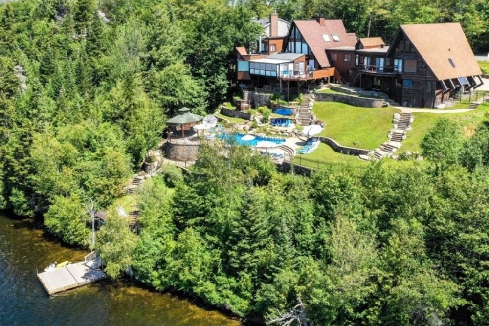 A bird's eye view of a spacious luxury lakefront estate, swimming pool, and dock.