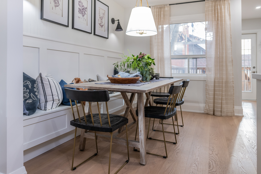 Dining area with banquet seating, wainscoting on the wall, streamlined chairs and a simple shade chandelier gives the room a polished and intimate vibe as featured on Property Brothers: Forever Home on HGTV Canada