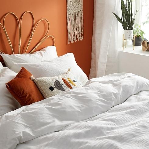 White bedding in a room painted bright orange.