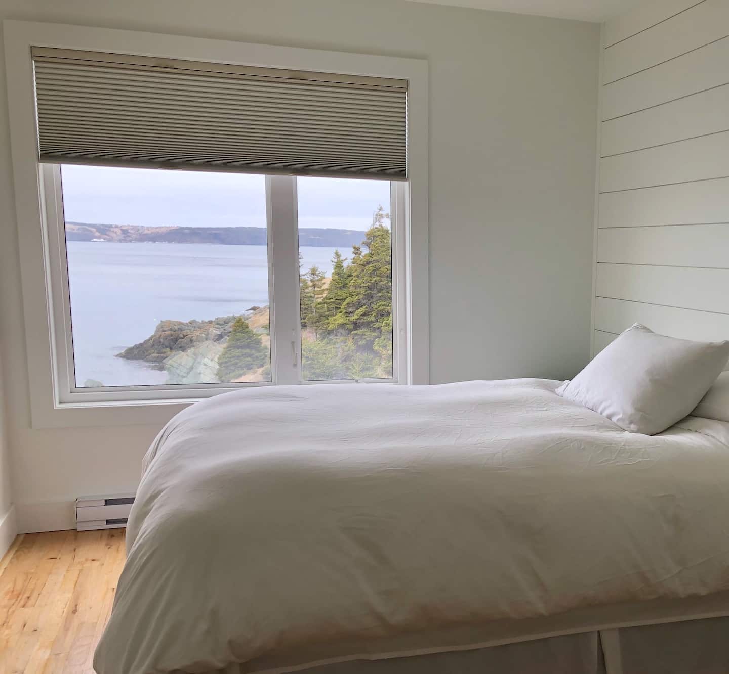 White bedroom with picture window of Conception Bay, Newfoundland