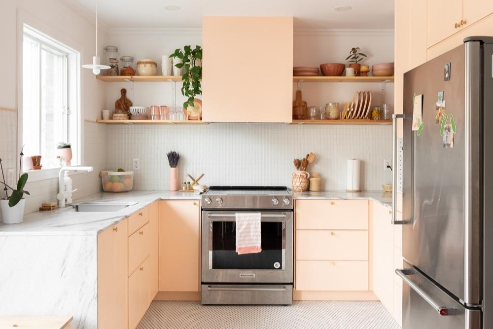 A kitchen with pinky peach cupboards and white marble countertops
