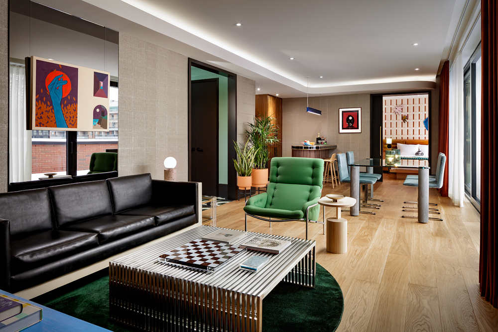 hotel suite black leather sofa bottom left, green chair, table and dining chairs in, bedroom in background