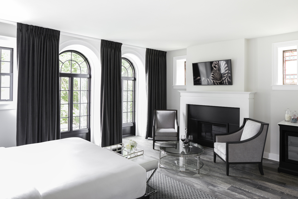 white and black bedroom with black curtains, arched windows, zebra pic above the fireplace