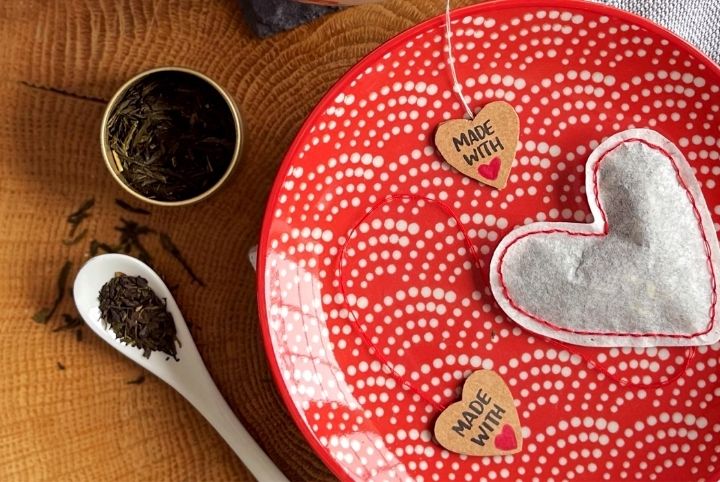 A canister of tea, a heart-shaped tea bag and a red and white plate