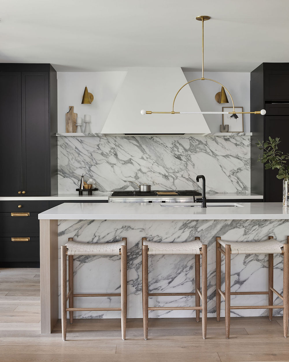 Marble kitchen with black cabinetry and pale wood