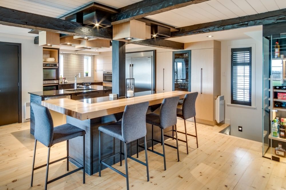 A modern luxury kitchen with a wooden island and four grey stools