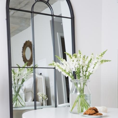 A mirror in a studio apartment behind a small white dining table