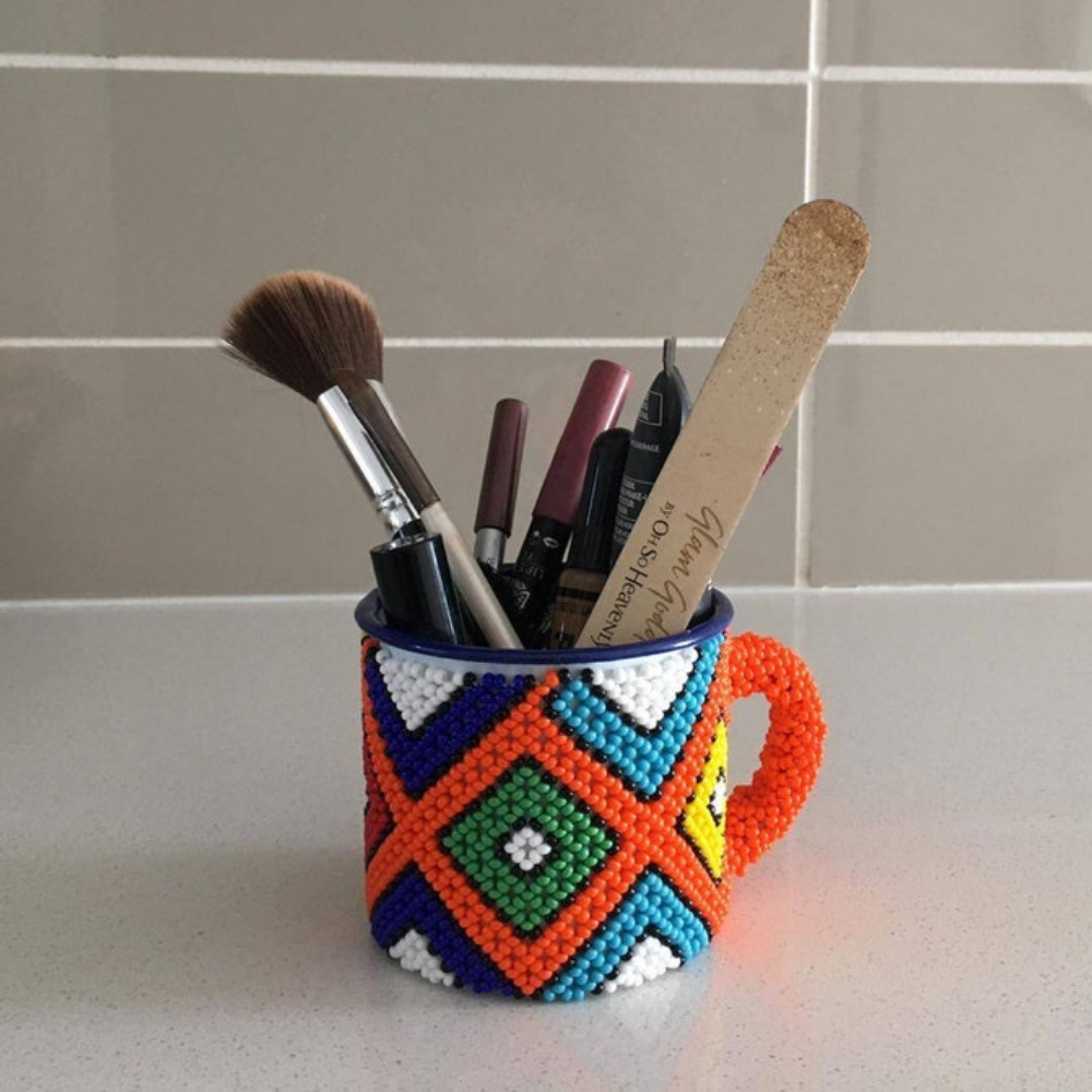 Colourful beaded mug in the iconic Ndebele beadwork style, distinguished by its highly vibrant colours and strong geometric patterns.