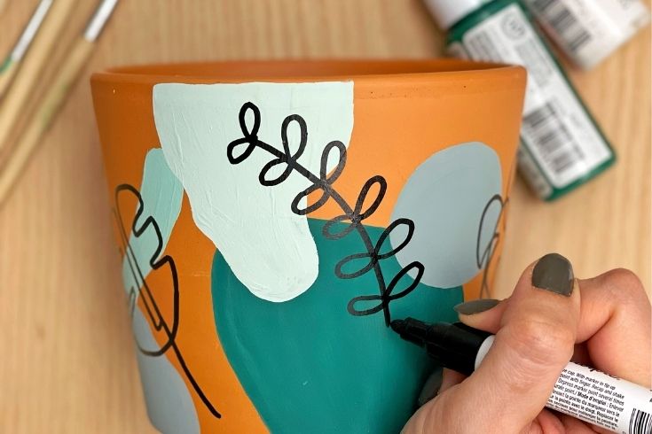 Person doodling on clay pot 