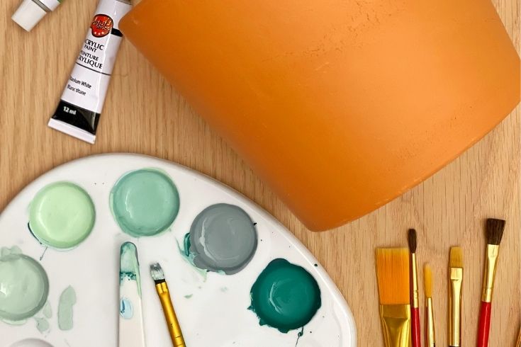 Paint supplies, brushes, and terracotta pot 