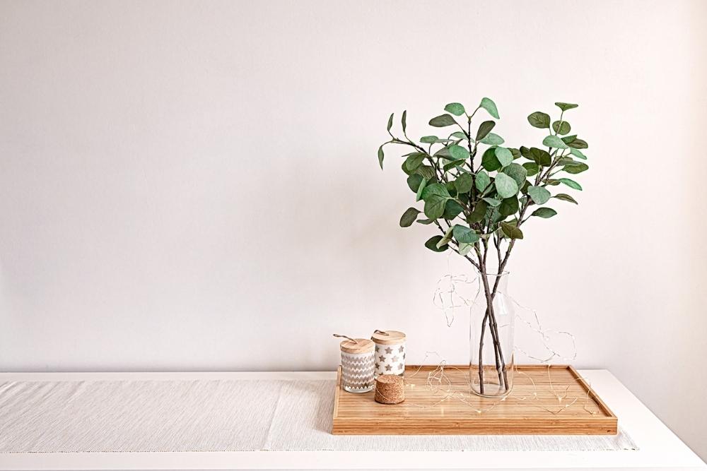 Eucalyptus in a vase, sitting on a table top beside candles