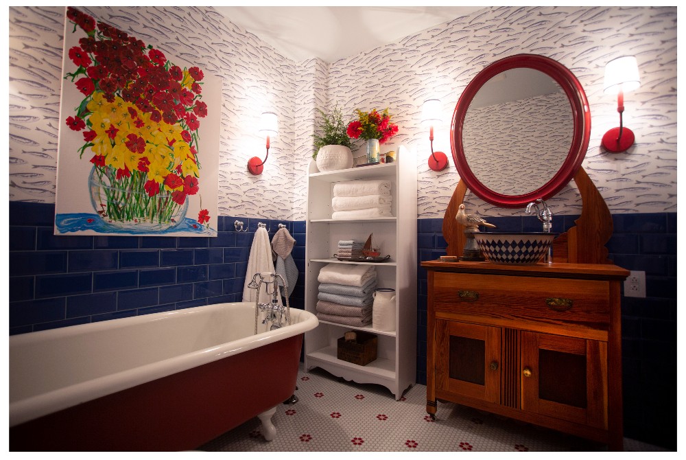 Bathroom with blue tile, fish wallpaper and red accents