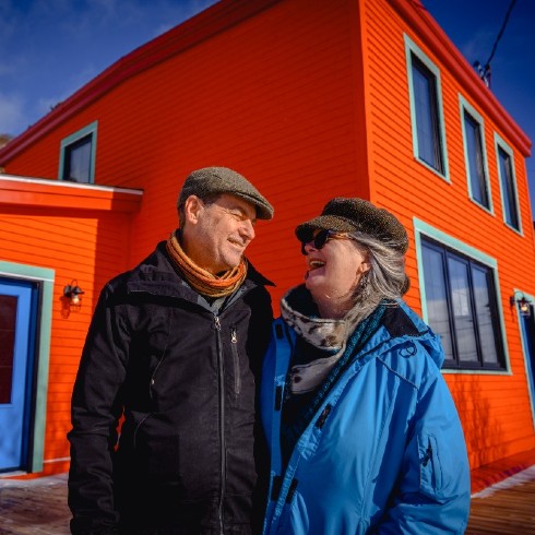 Couple in Newfoundland standing in front of renovated orange home