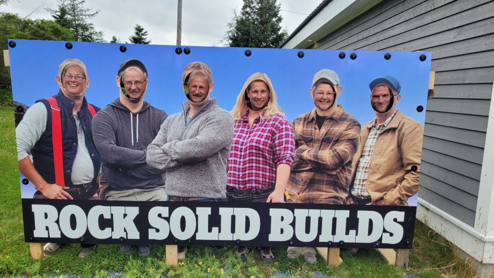 Rock Solid Builds cast being silly with a Rock Solid Builds sign