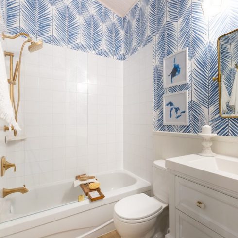 All white bathroom with gold finishes and blue statement wallpaper
