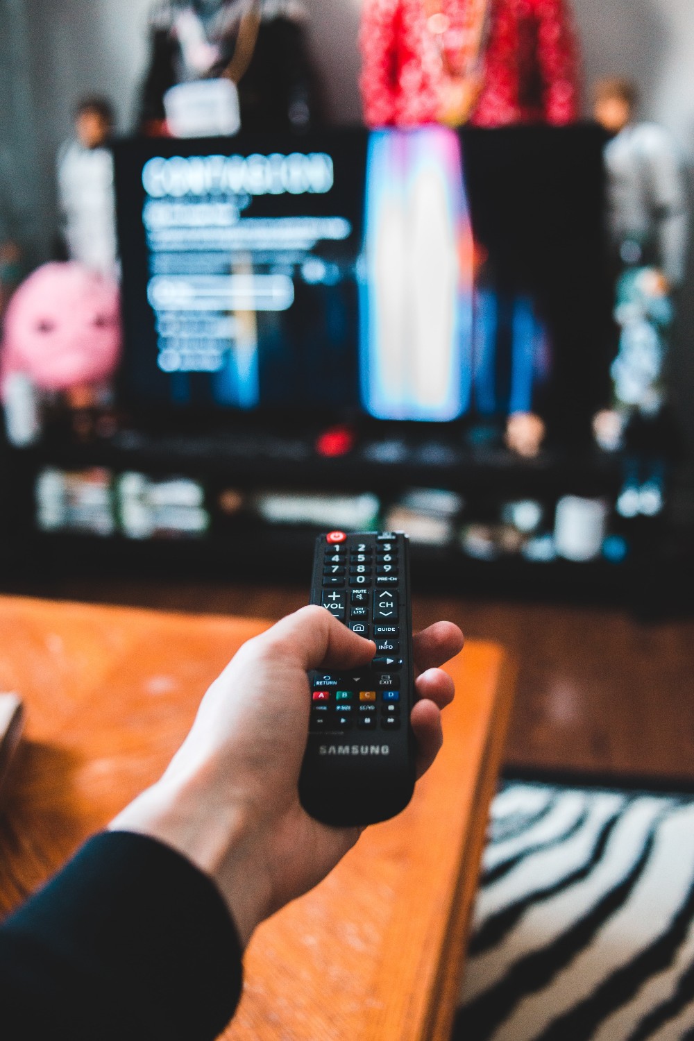 Hand holding tv remote towards tv turned on
